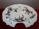 a white bowl with flowers on it on a red table