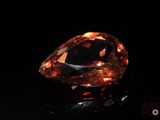 a close up of a large orange diamond on a black surface