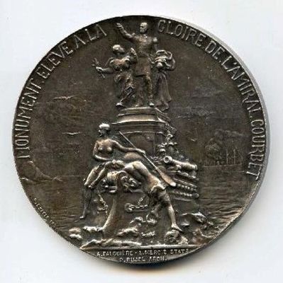 une vieille médaille surmontée d'une statuette, posée sur une surface blanche