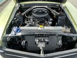une voiture verte dont le capot est ouvert et dont le moteur se trouve dans le coffre