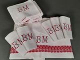 un gros plan sur une pile de serviettes blanches ornées de lettres rouges