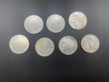 six silver coins of different sizes and shapes on a black surface