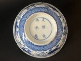 blue and white bowl with oriental writing on it on a black surface