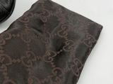 a black purse and a brown scarf on a white table