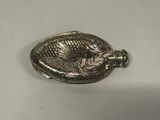une assiette en argent décorée d'un poisson, posée sur une table