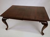 a table with two leaves on the legs and a wooden top
