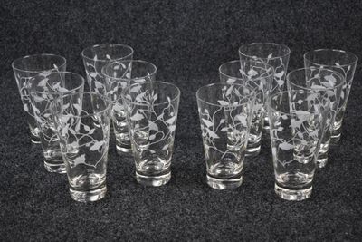six etched glass glasses are lined up on a black surface