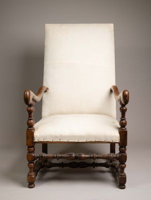 une vieille chaise avec une assise rembourrée blanche et des pieds en bois