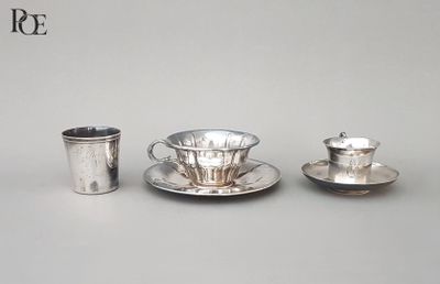 une tasse et une soucoupe en argent posées l’une à côté de l’autre