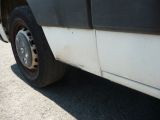 a white truck with a flat tire parked on the side of the road