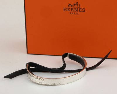 an orange box with a silver bracelet on it and a black ribbon