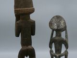 two wooden figurines of a man and a woman with a basket on their head