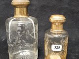 two small glass bottles with gold lids sitting on a black surface
