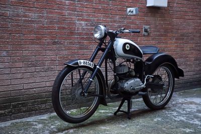 a black and white motorcycle parked in front of a brick wall
