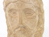 une tête d'homme sculptée dans la pierre, avec une croix sur le front