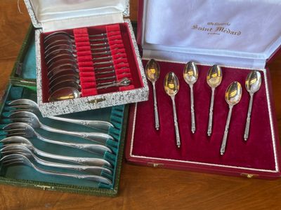 several spoons and forks are in a case on a table