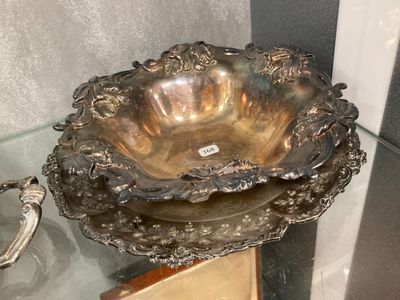 a silver bowl sitting on a glass table next to a pair of silver spoons