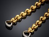 a gold chain with a heart shaped clasp on a black background