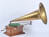 un gramophone à l'ancienne posé sur un support, sur fond blanc