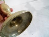 une personne tenant une cloche en laiton à la main