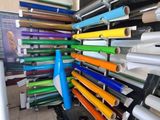 de nombreux rouleaux de papier coloré posés sur un présentoir dans un magasin