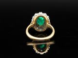 an emerald and diamond ring on a black surface