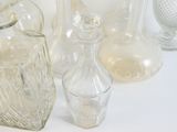 de nombreux vases en verre posés sur une table, sur fond blanc