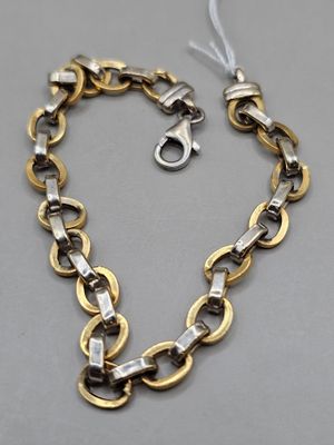 un gros plan d'un collier en or et en argent posé sur une surface grise
