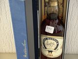 une bouteille de whisky vide dans une boîte bleue posée sur une table