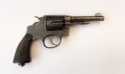 un vieux revolver posé sur une surface blanche, avec un fond blanc