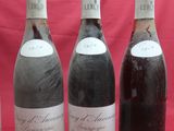 three bottles of wine sit next to each other on a red background