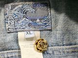 the back of a pair of jeans with a gold rose pin on it