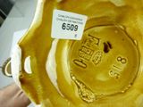 someone is holding a yellow vase with a label on it