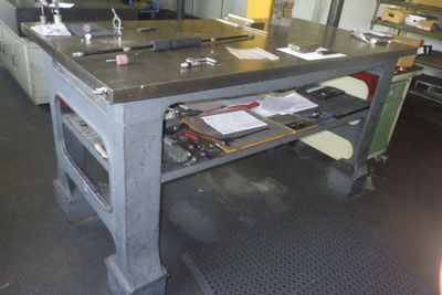 une photo d'un établi dans une usine, sur lequel se trouvent de nombreuses pièces en cours de fabrication