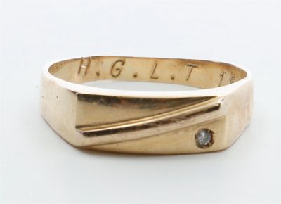 une bague en or sertie d'un diamant, posée sur une surface blanche
