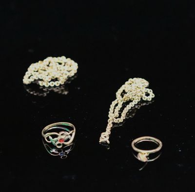 trois bagues, un collier et une bague posés sur un fond noir