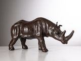sculpture en bronze représentant un rhinocéros debout sur une surface blanche
