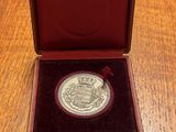 a silver coin in a red case sitting on a wooden table