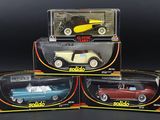 three boxed toy cars are sitting in a box on a black surface