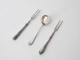 three forks and a spoon on a white table