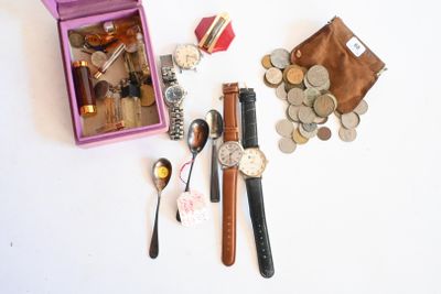 une boîte rose sur laquelle sont posés une montre, une cuillère et quelques pièces de monnaie