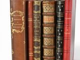 several old books are stacked on top of each other on a white surface