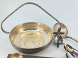 a silver bowl with spoons and spoon rest on a table