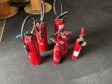 several fire extinguisors are lined up on a tiled floor