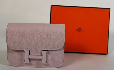 Le sac Hermès est posé sur la table, à côté de la boîte orange.