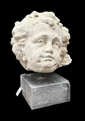 marble head of a woman with curly hair on top of a stone block