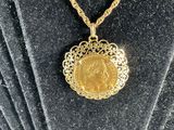 a gold necklace with a coin on it