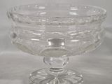 a glass bowl on a stand on a white surface