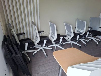 Plusieurs chaises de bureau sont alignées en rang dans une pièce vide