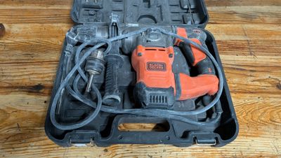 une perceuse électrique orange et noire dans un coffret posé sur une table en bois